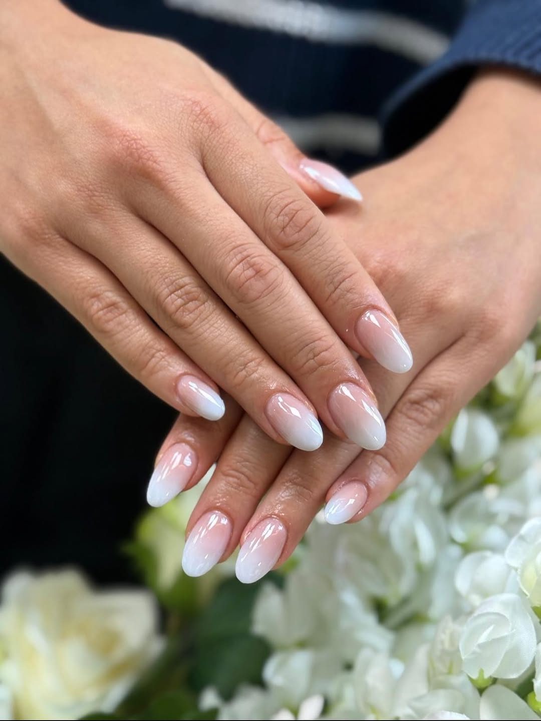 Babyboom-nagels in amandelvorm, handen op witte rozen